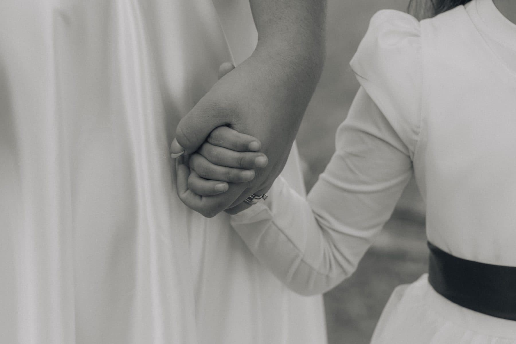 Two people standing arm in arm, hands clasped.