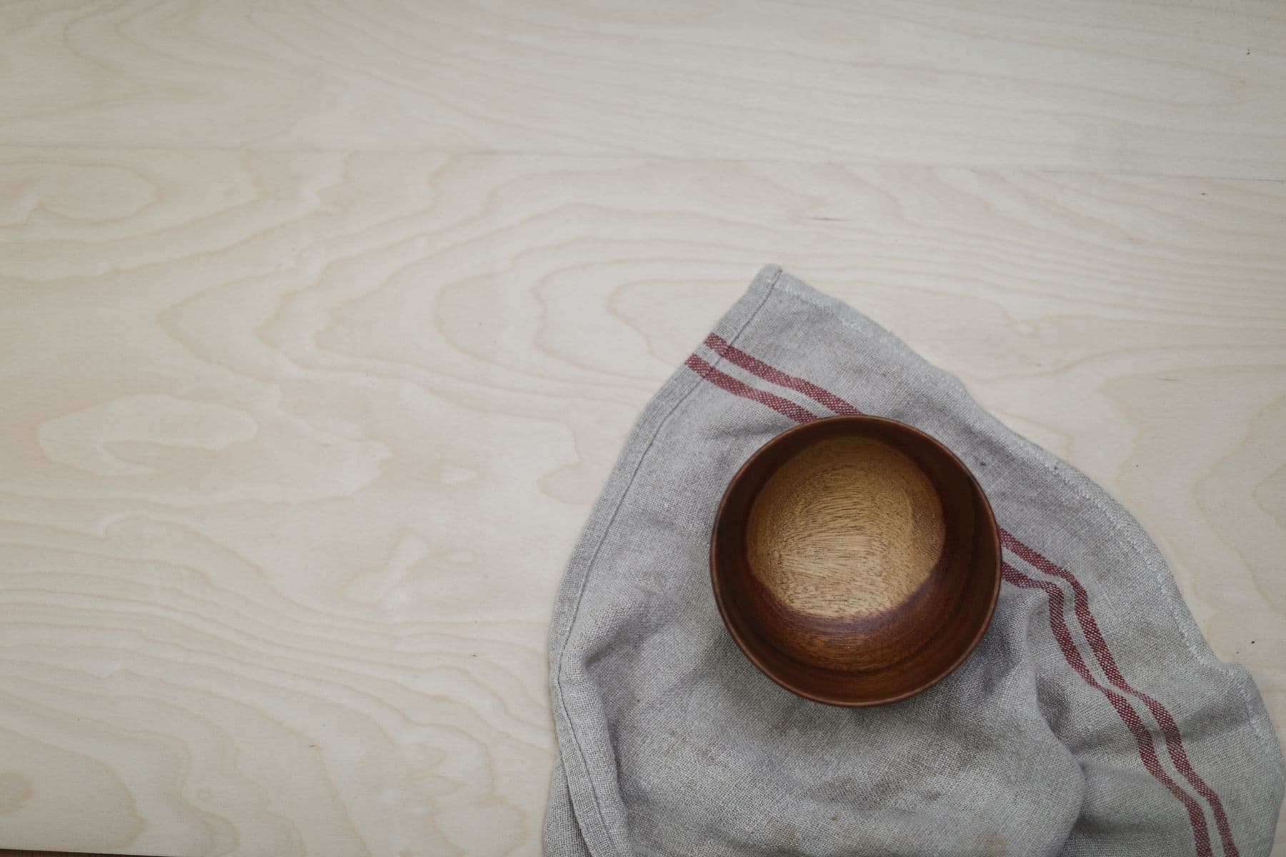 A small wooden bowl resting on folded linen.