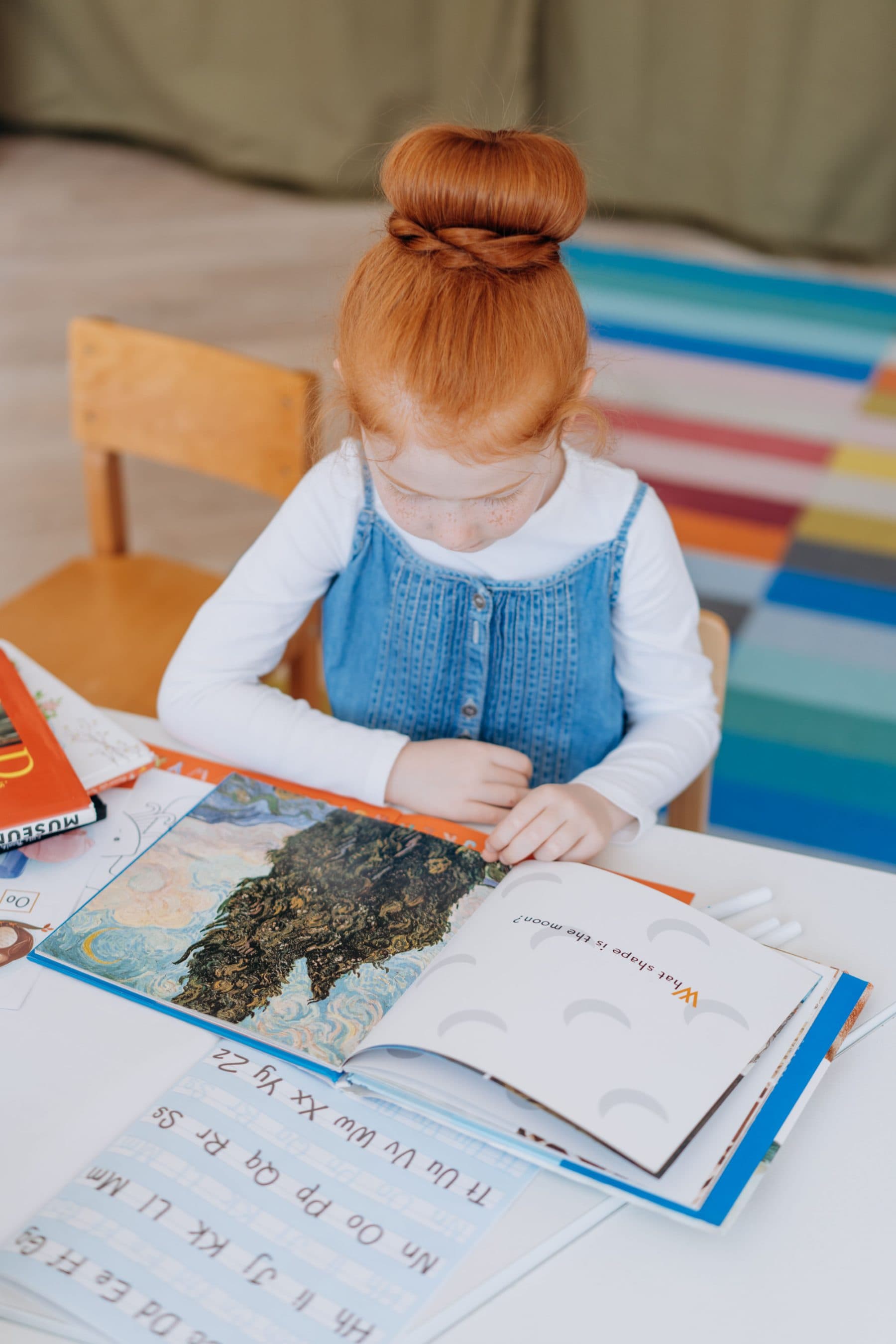 A child at a desk working over an open illustrated book.