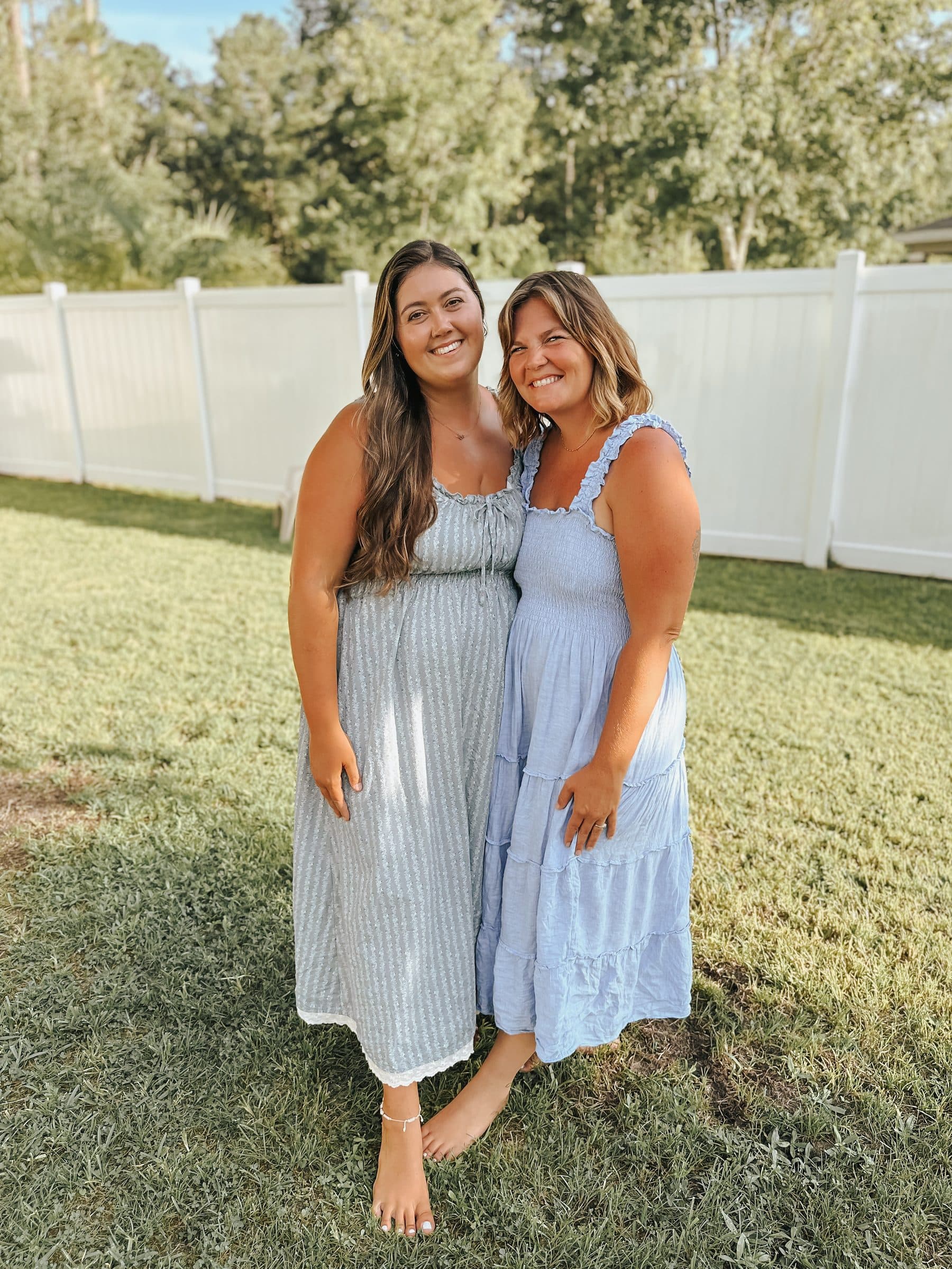 Lily and Bethany, the co-directors, standing together on a sunlit lawn in summer dresses, smiling.