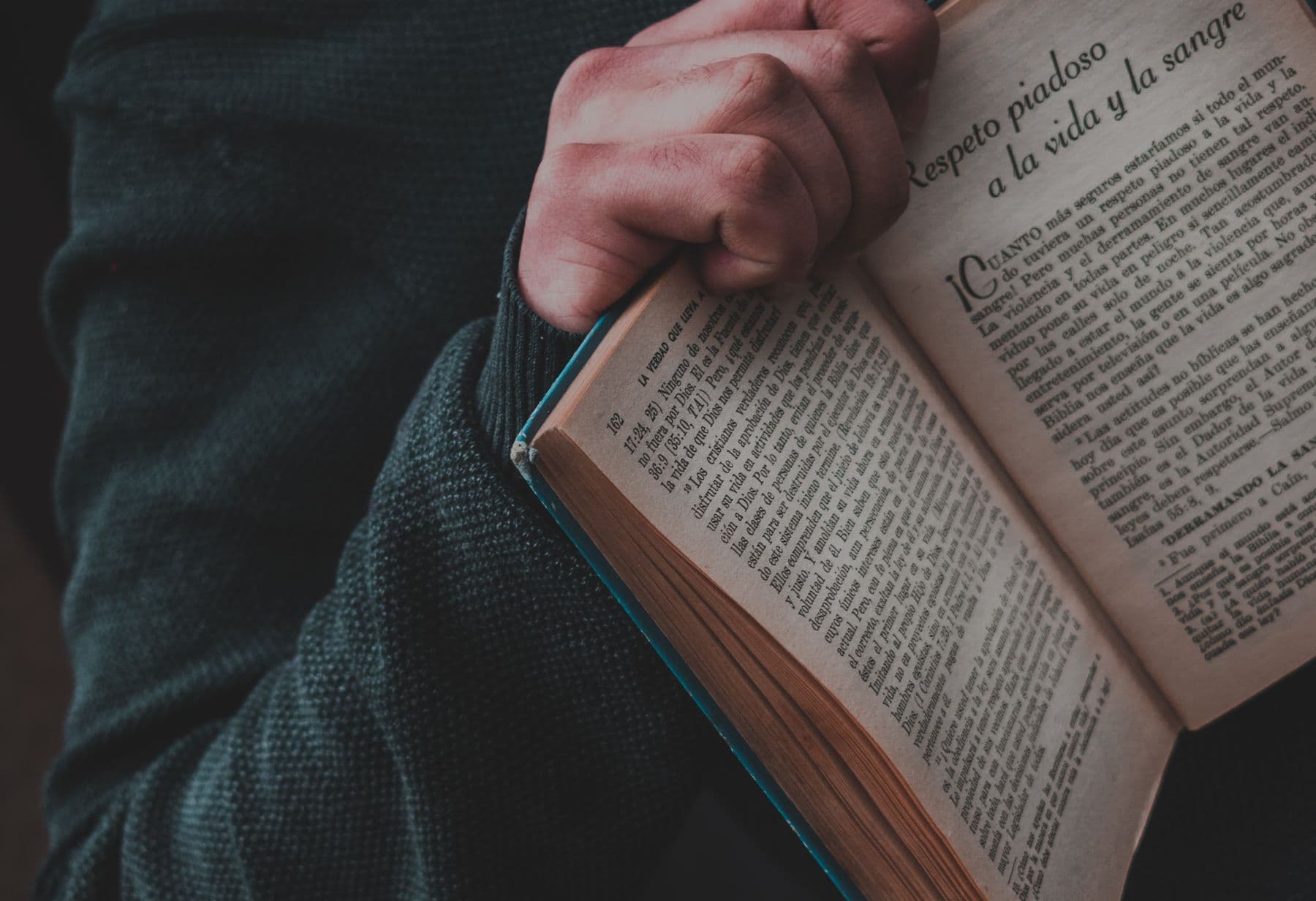 Hands holding an old book open.